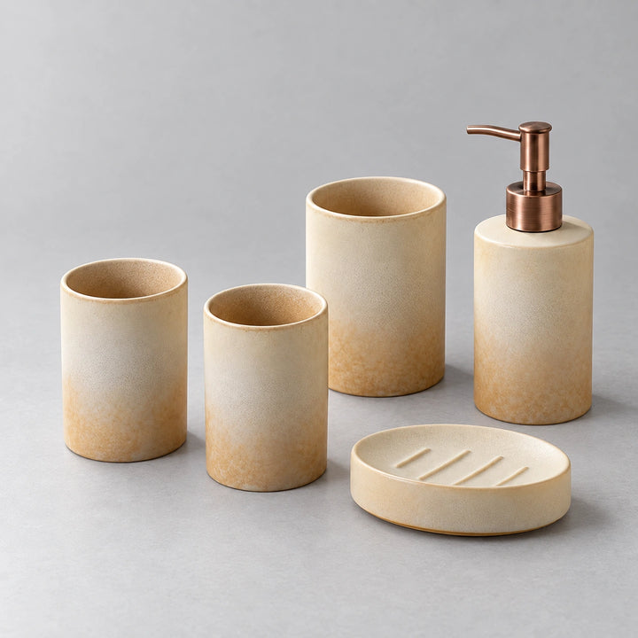 Two beige cups, holder, bronze-tone pump dispenser and ridged soap dish in five-piece set.