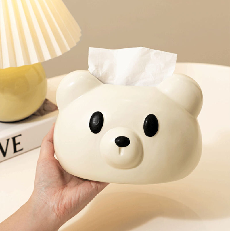 Tissue box shaped like a bear with a hand holding it, on a blurred background