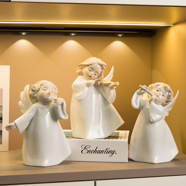 Three white angel figurines with different poses on a shelf.