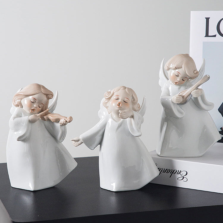 Three white angel figurines on a black surface with a white background