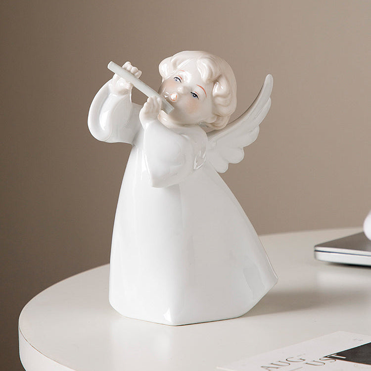 White angel figurine with wings holding a flute on a round white surface with a beige background