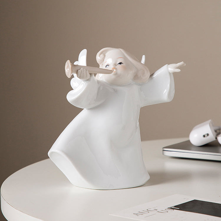 White angel figurine playing a flute on a beige surface with a neutral background