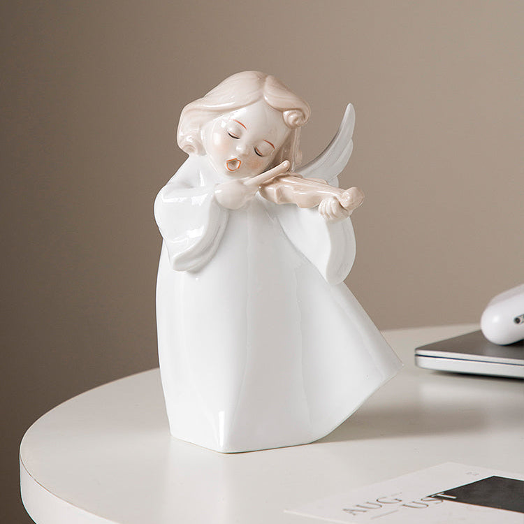 White angel figurine playing a violin on a white surface with a neutral background
