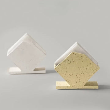 Two house-shaped ceramic napkin holders with open slots, pale yellow speckled in front and white behind