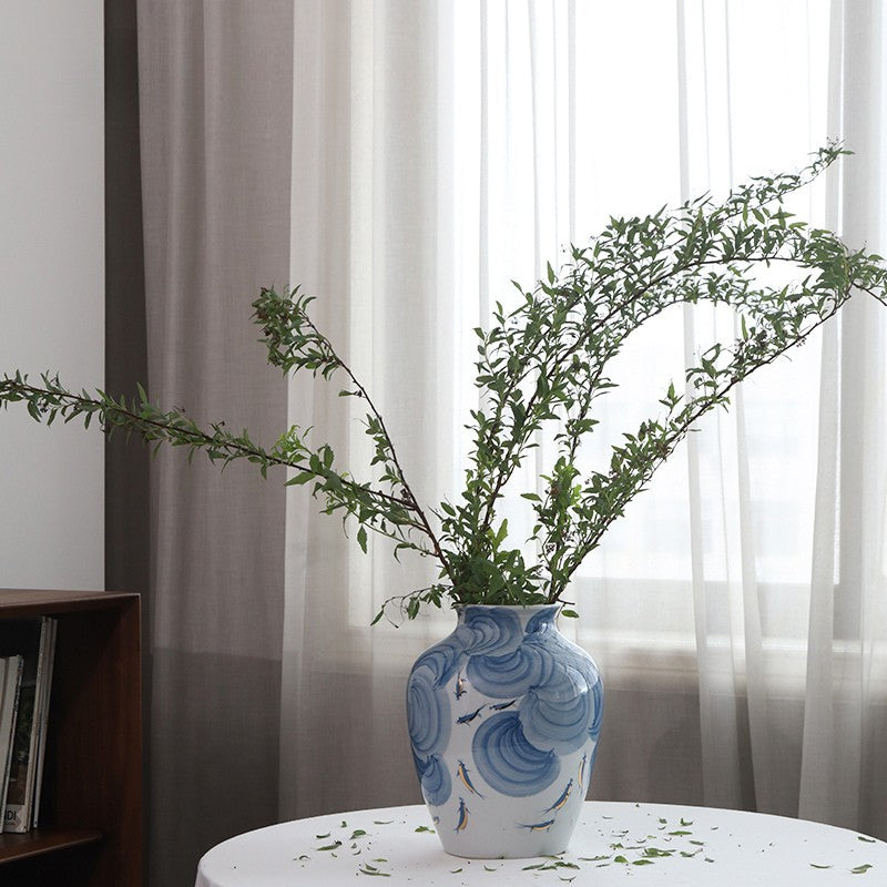 Blue and white ceramic vase with wave design on a wooden surface