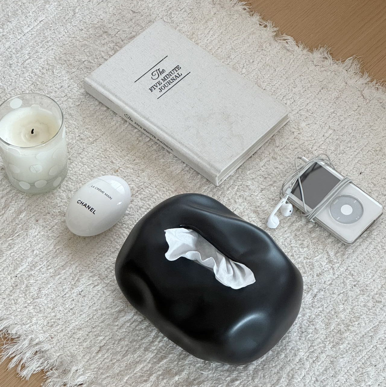 Black lip-shaped product, white candle, and silver iPod on a textured surface
