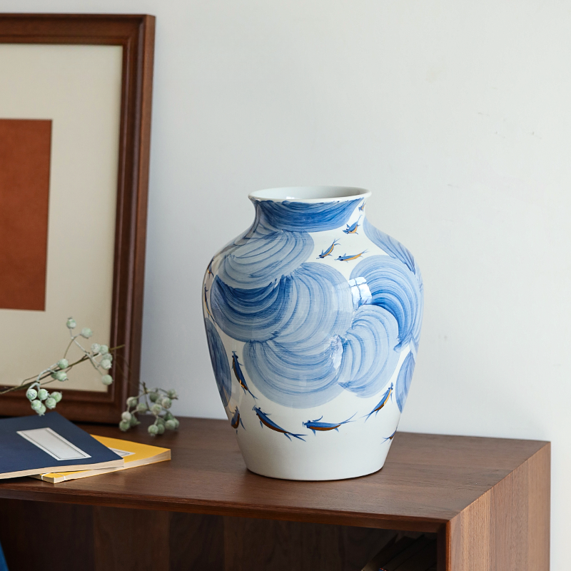 Blue and white ceramic vase with wave design on a wooden surface