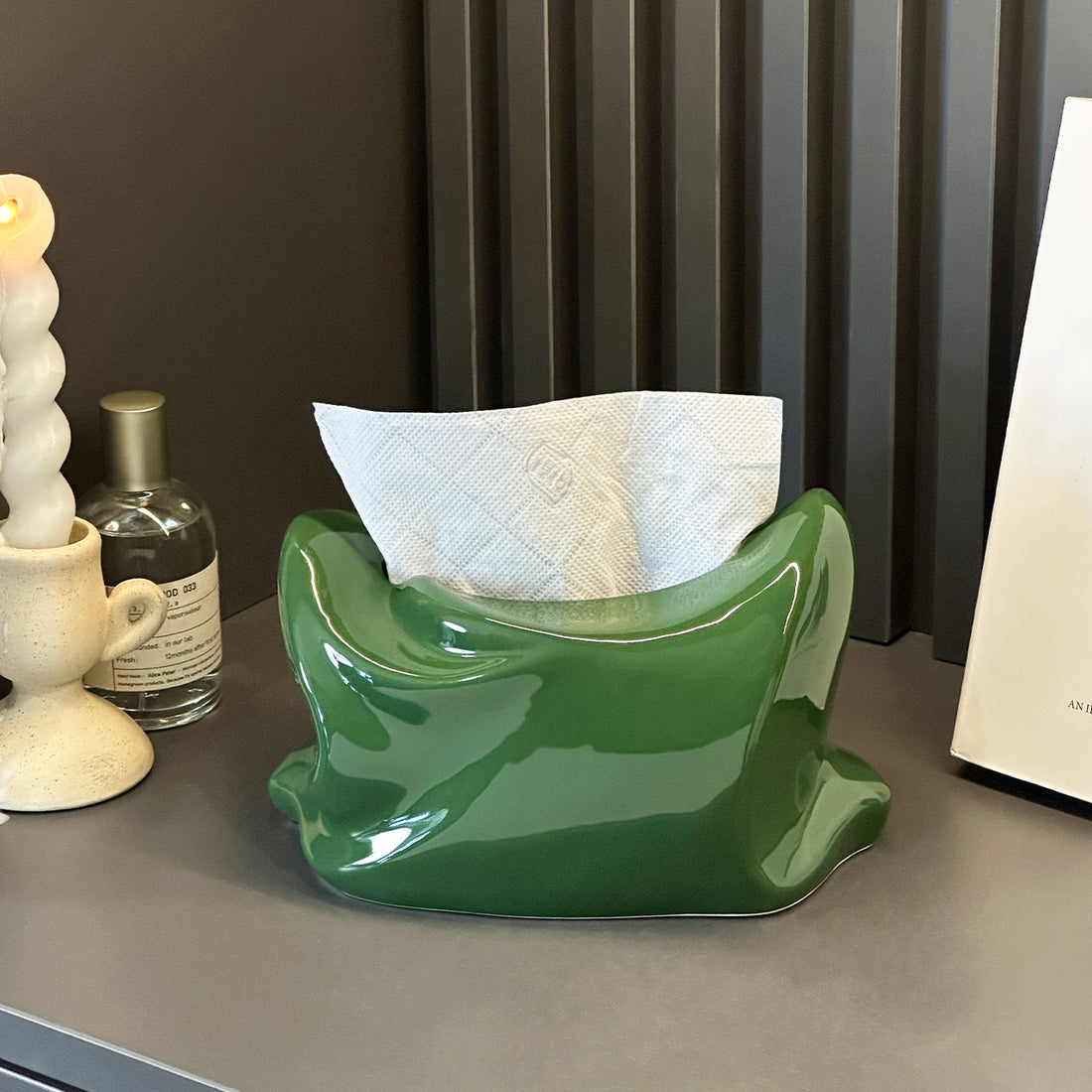 Green ceramic vase on a white surface with a dark background