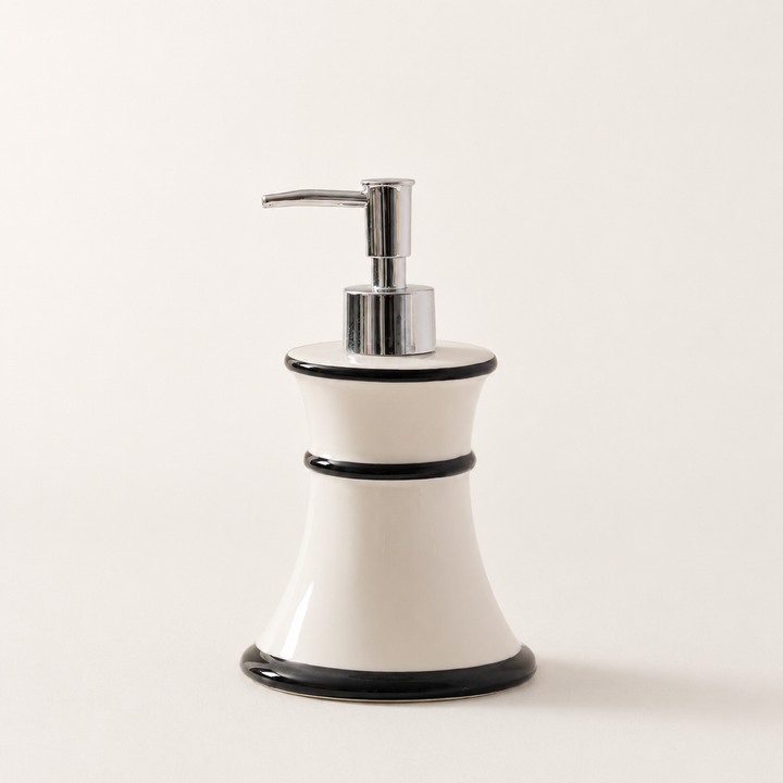 Tall ceramic soap dispenser in glossy white with three black contour bands and silver pump against studio backdrop
