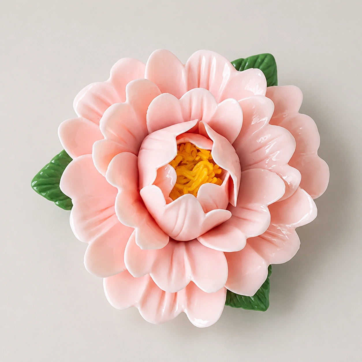 Aimant pivoine en céramique rose poudré sur fond neutre clair.