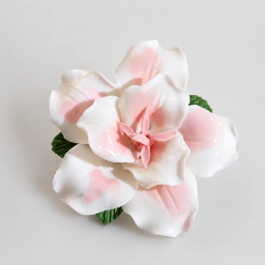 Blush pink glazed ceramic lily refrigerator magnet on a light pearl-gray background.