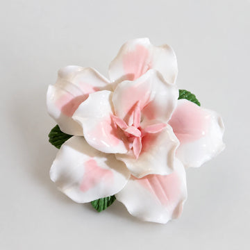 Blush pink glazed ceramic lily refrigerator magnet on a light pearl-gray background.