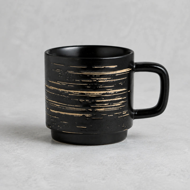 Ink Black brushed-line ceramic mug on a cool pearl-gray studio background.