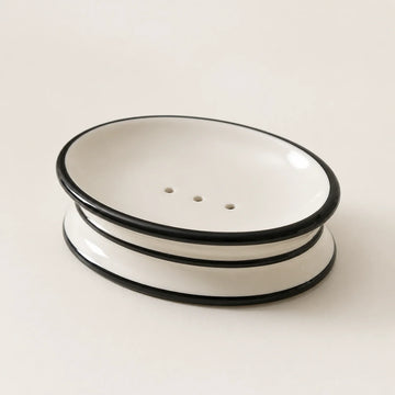 Oval warm ivory ceramic soap dish with black trim and three drainage holes
