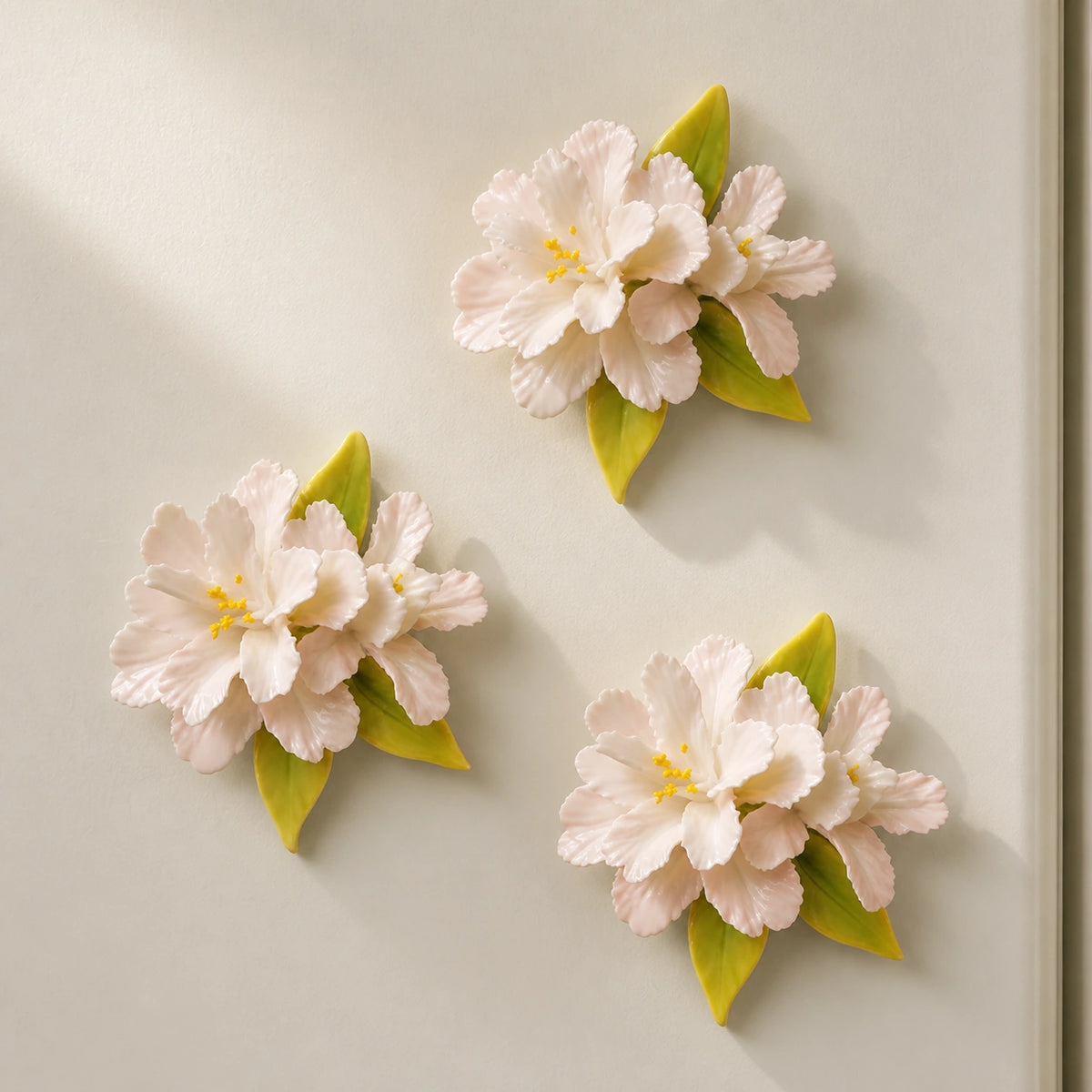 Three blush-white ceramic crabapple magnets arranged as a gallery-like trio on an ivory refrigerator.