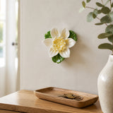 Petite fleur de lotus – Accent jaune doré, fleur en céramique mise en scène sur un mur intérieur
