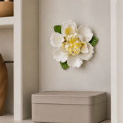 Medium Ruffled Peony Ceramic Wall Flower in Golden Yellow Accent mounted above a matte storage box in a bookshelf alcove.