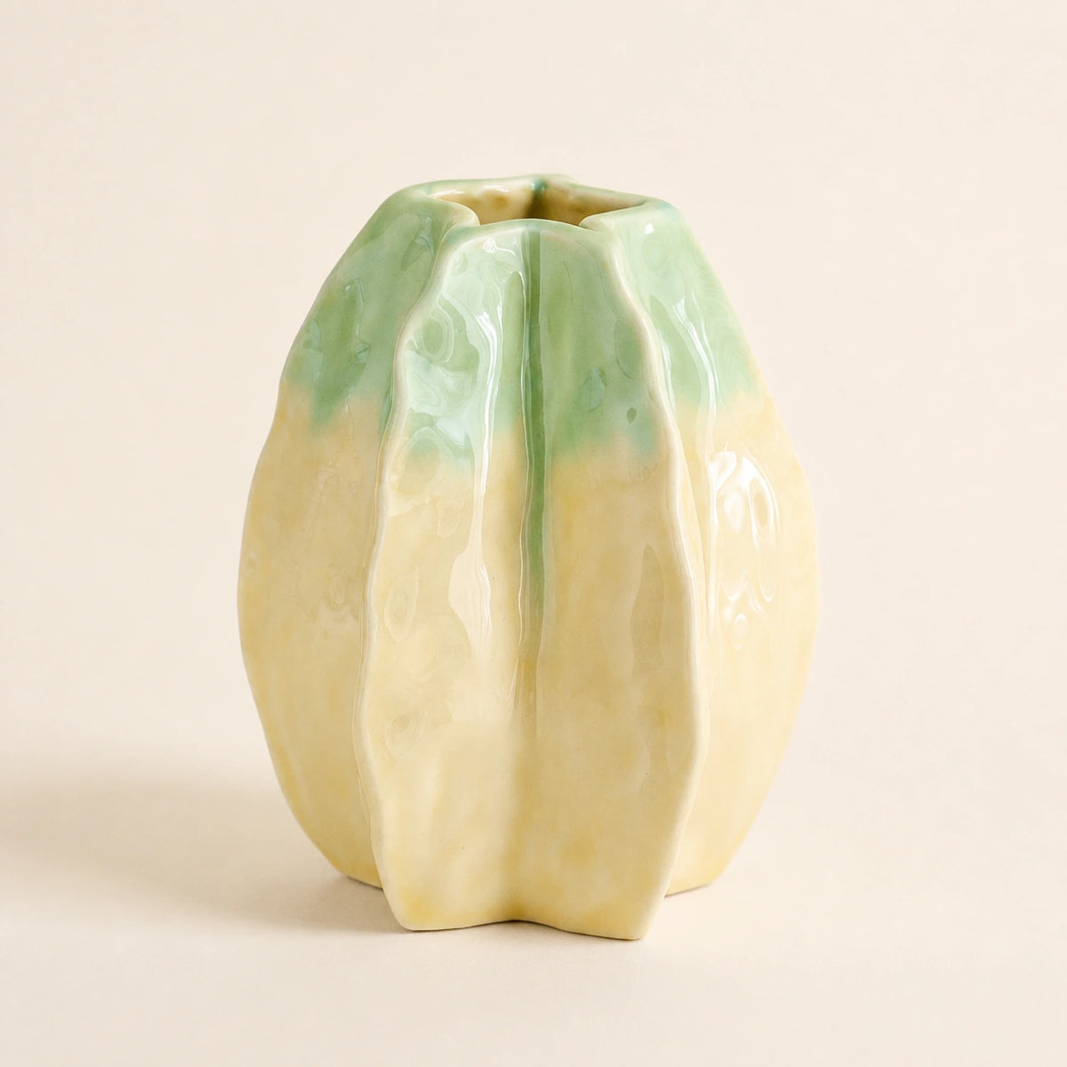 Medium starfruit-inspired yellow-green ceramic vase against a warm ivory background.