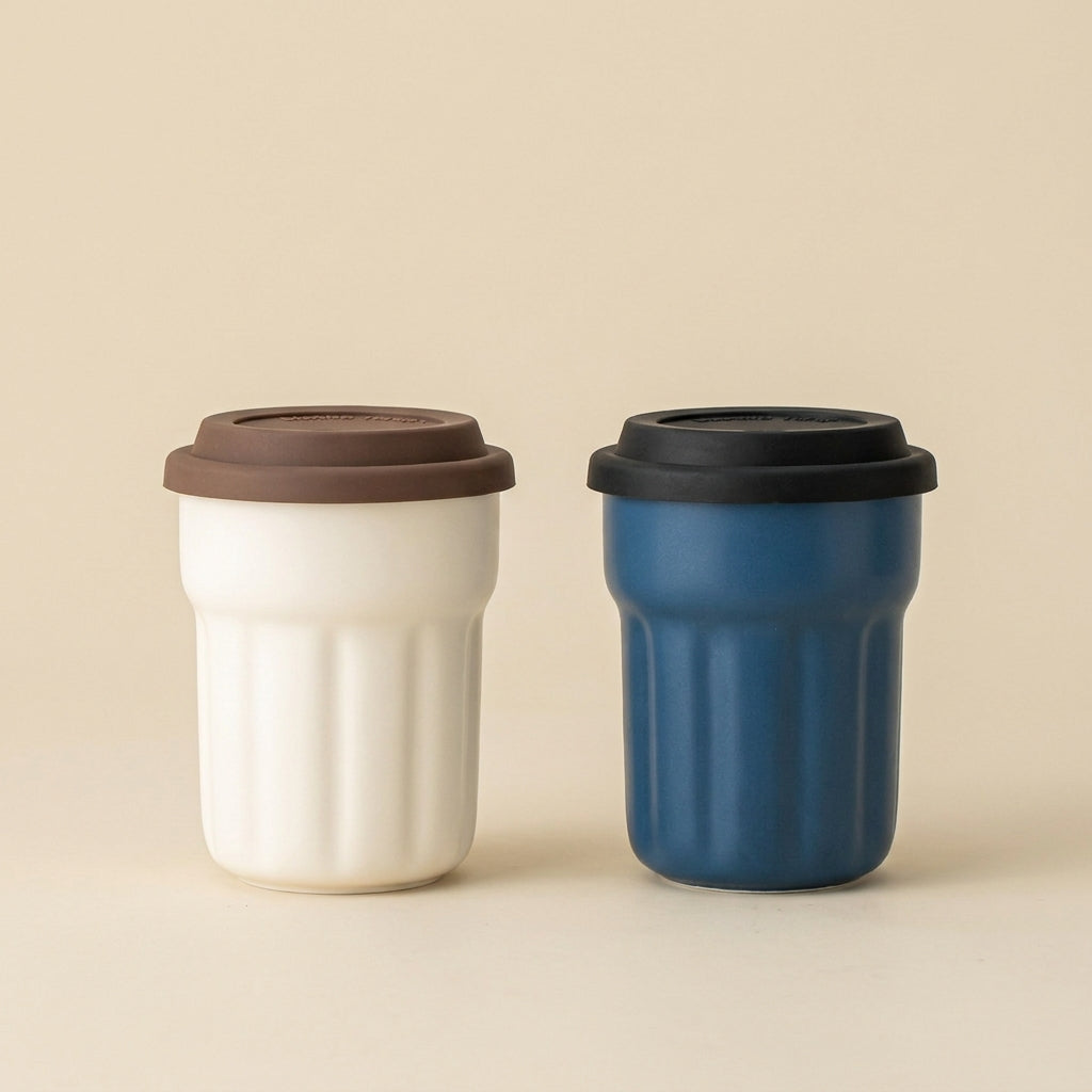 Cream and navy blue fluted ceramic travel mugs with brown and black lids