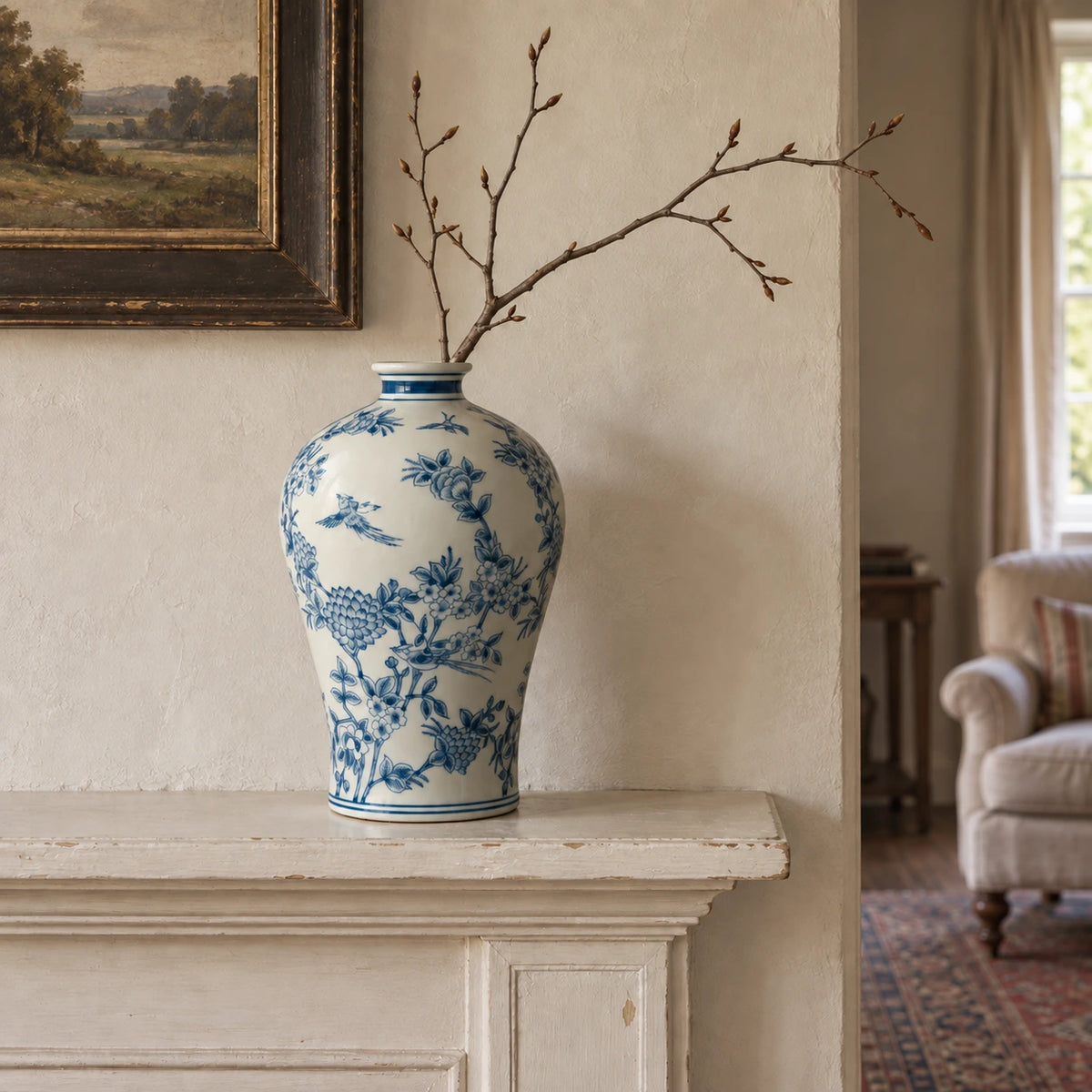 Hohe blau-weiße Vase mit einem knospenden Zweig auf einem patinierten Kaminsims.