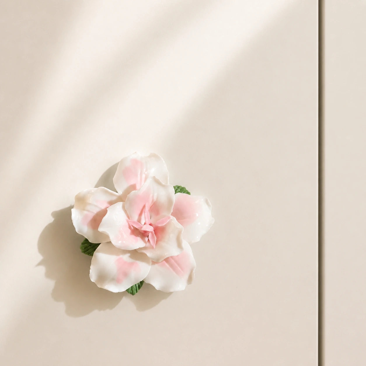 Blush pink ceramic lily magnet styled alone on a warm ivory magnetic entry cabinet.