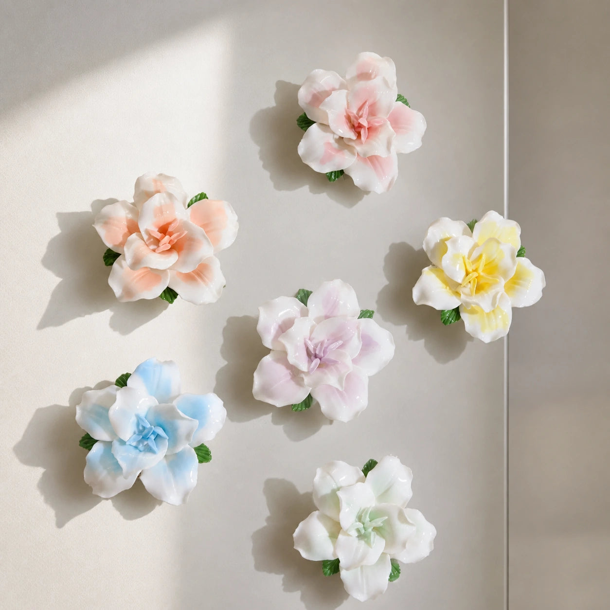 Six ceramic lily magnets arranged as an airy color composition on a pearl-gray kitchen panel.