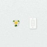 Petite fleur de lotus – Accent jaune doré près d’une plaque d’interrupteur pour l’échelle