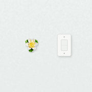 Petite fleur de lotus – Accent jaune doré près d’une plaque d’interrupteur pour l’échelle