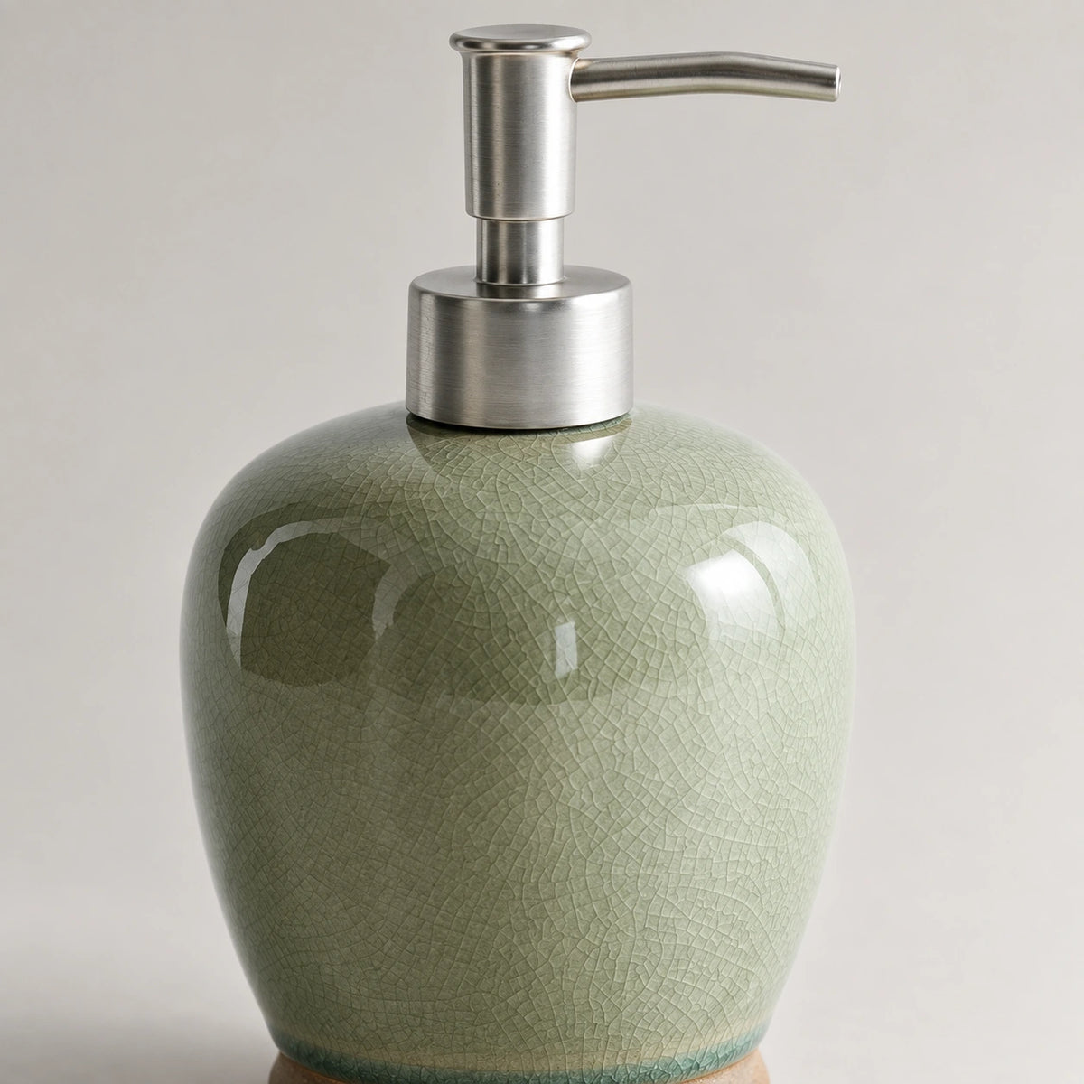 Close view of the silver-tone pump and fine crackle pattern on the glossy sage-green ceramic body.