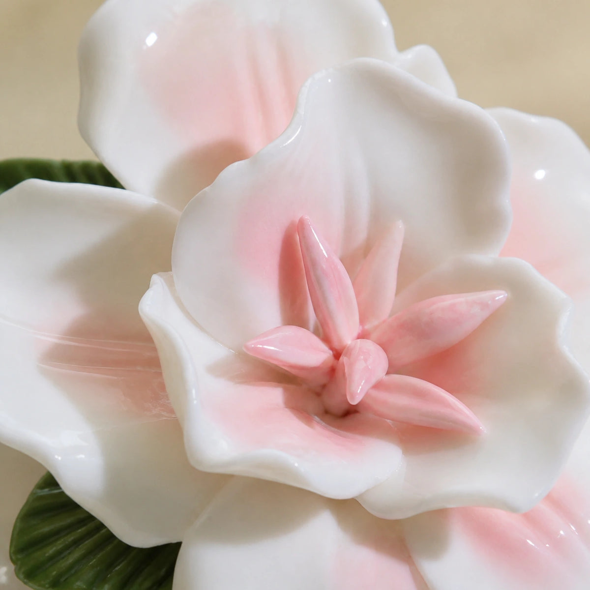 Close view of blush glaze, curled white petals and the pointed pink center of a ceramic lily magnet.
