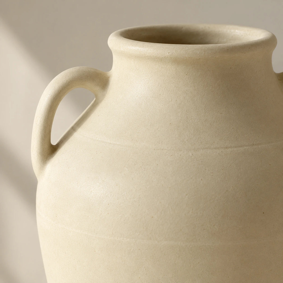 Close view of an ivory rolled rim, curved ear handle and fine matte grain