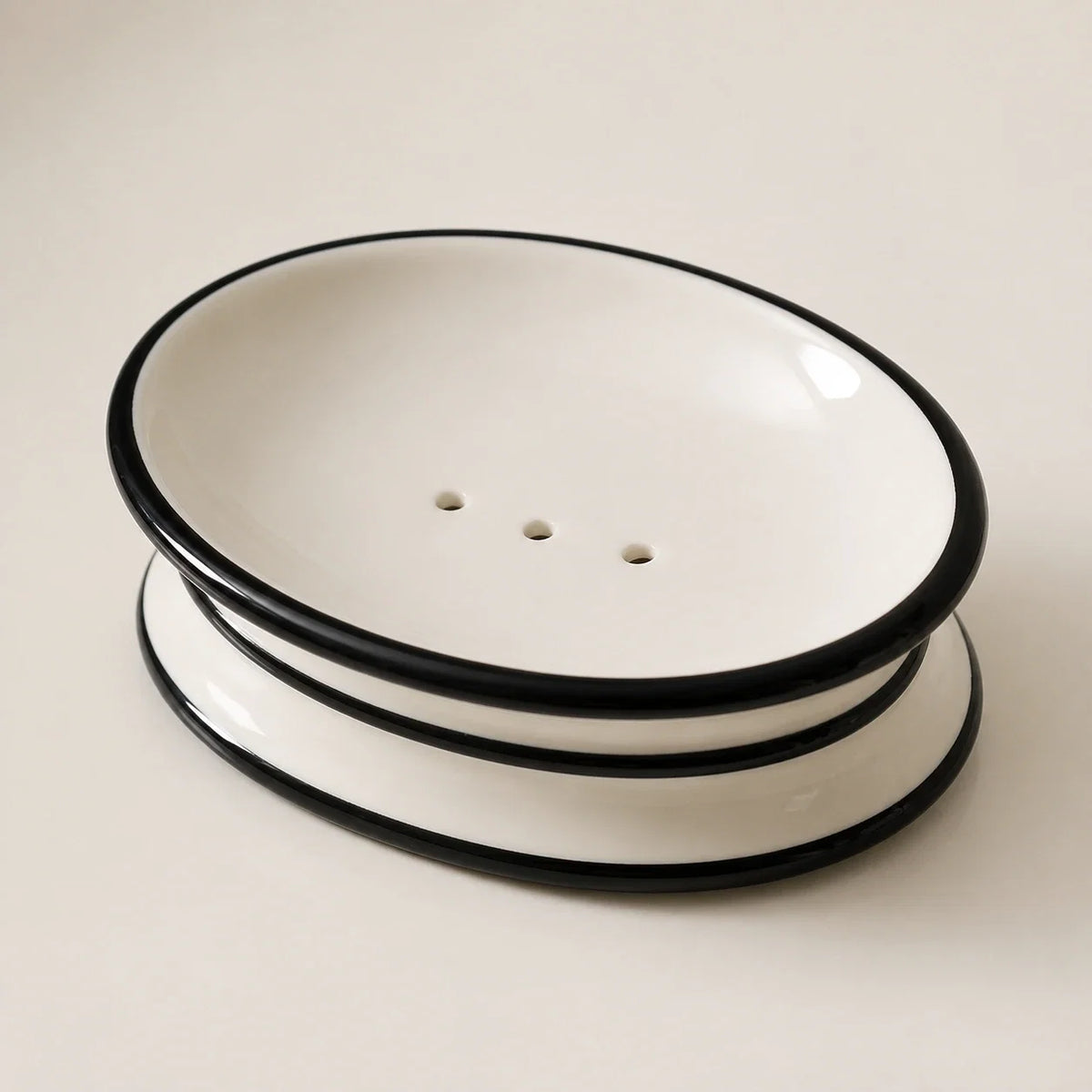 Close-up of the glossy ceramic soap dish, black trim, and three drainage holes