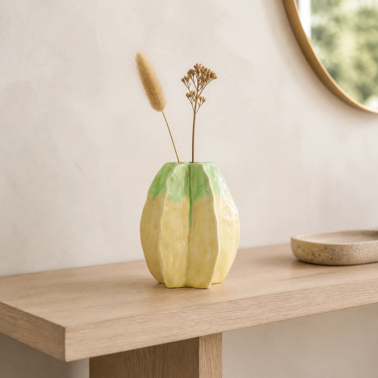Medium yellow-green lobed ceramic vase styled with dried stems on a pale oak console.