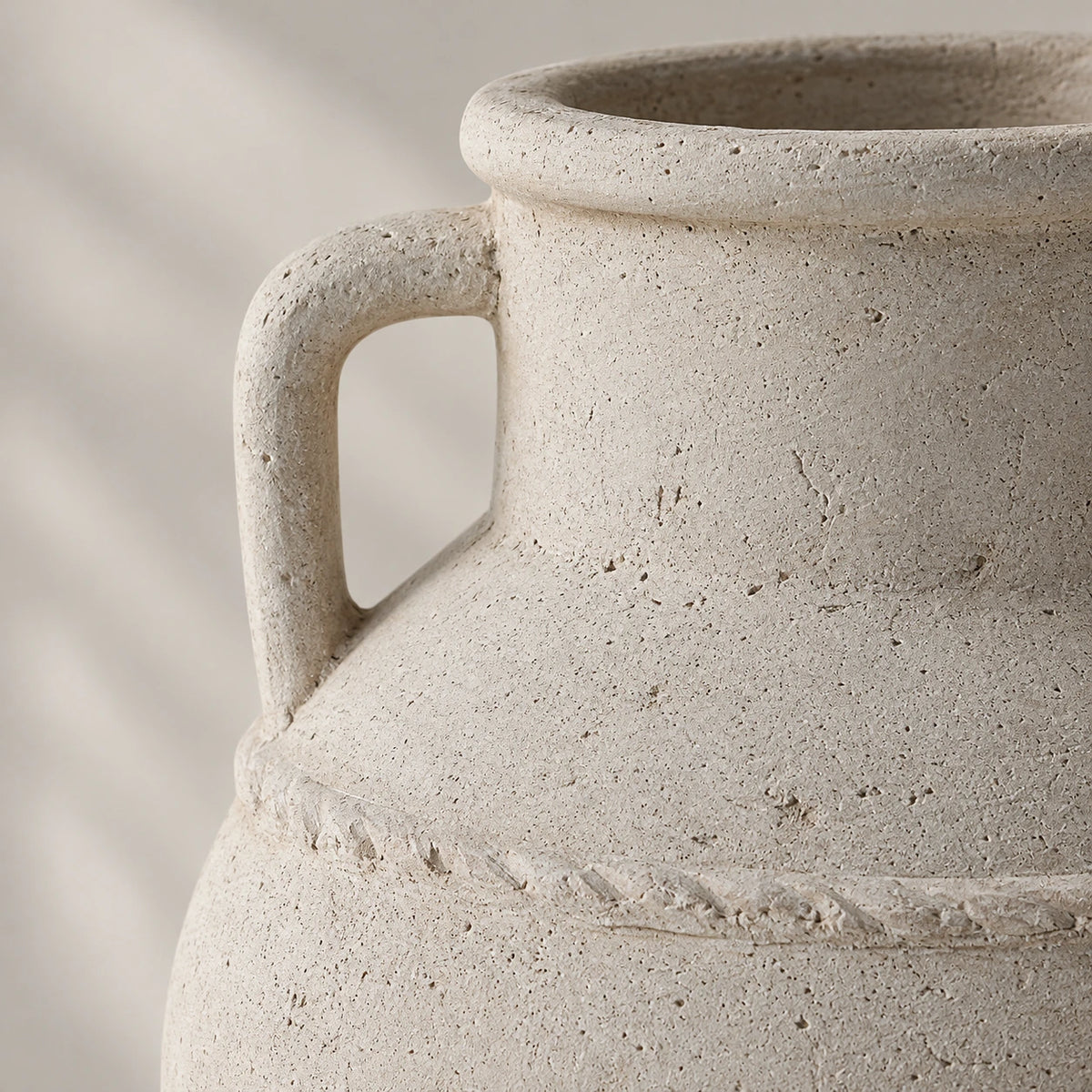 Close view of a rectangular ceramic handle, speckled rim and rough shoulder band