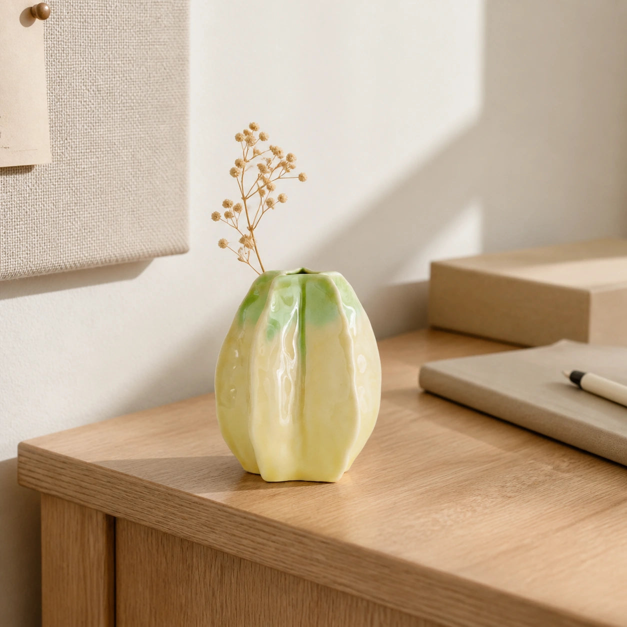 Small starfruit-inspired ceramic vase displayed on a compact wooden desk.