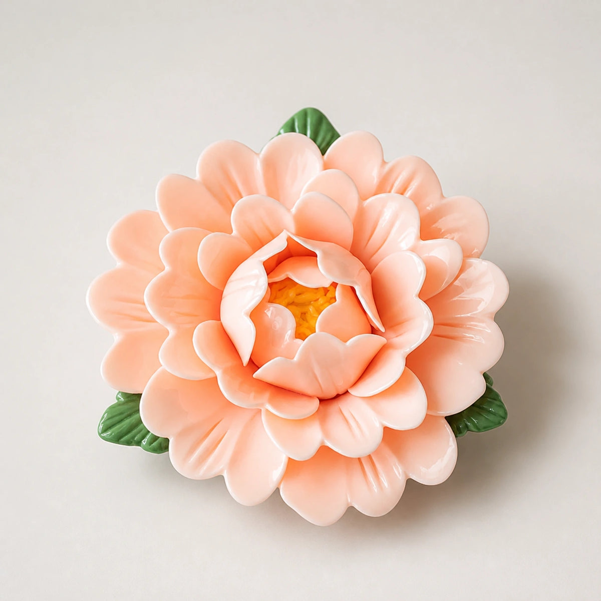 Aimant pivoine en céramique abricot doux sur fond neutre clair.