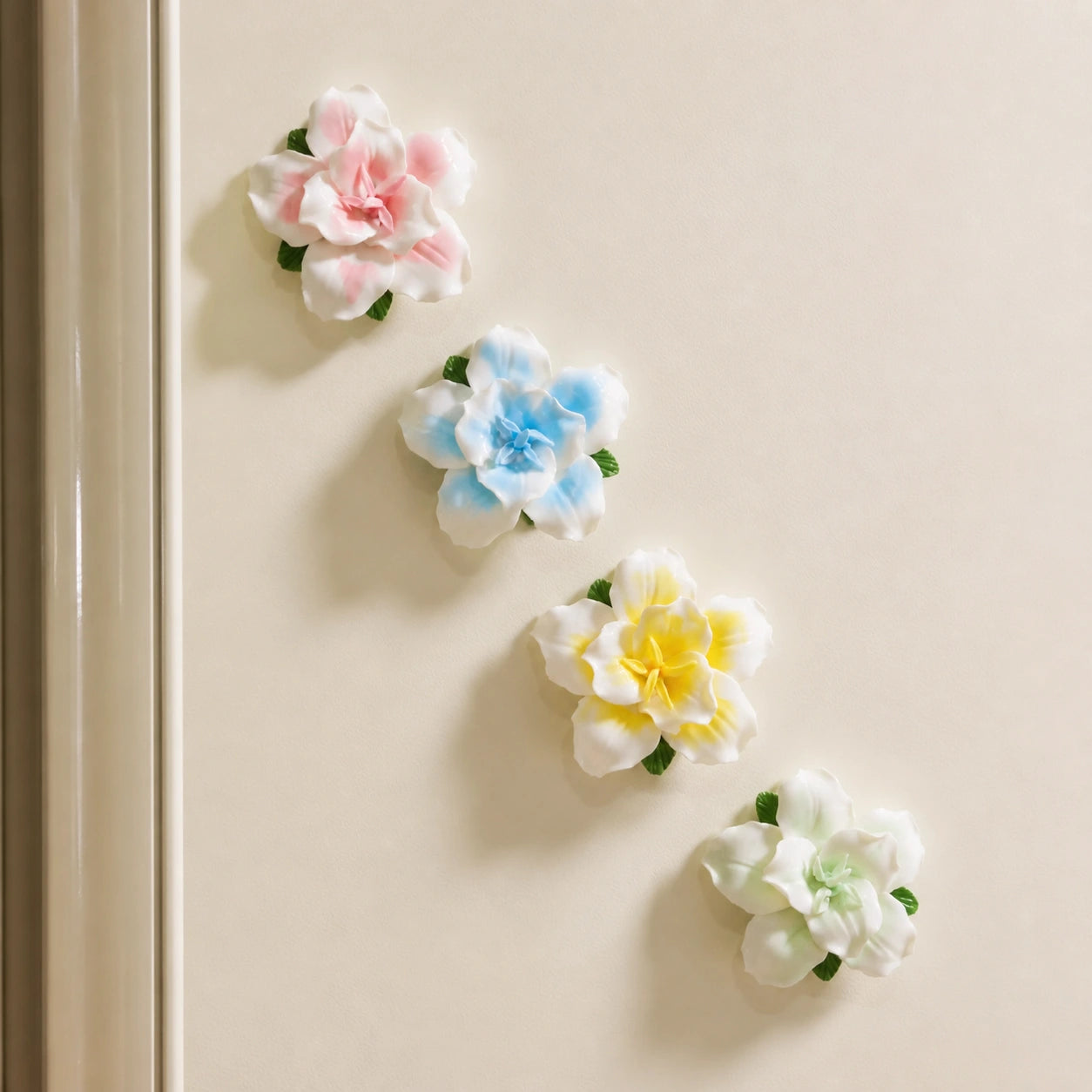 Blush pink, powder blue, butter yellow and pale green ceramic lily magnets arranged on warm ivory.
