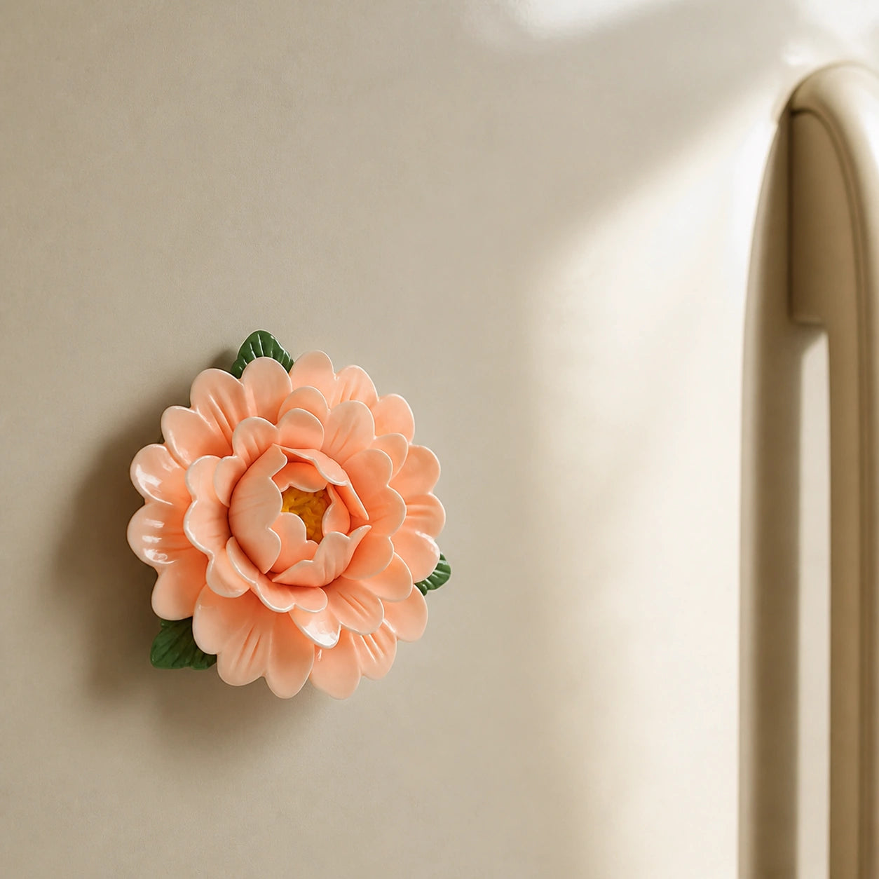 Aimant pivoine en céramique abricot doux sur un réfrigérateur beige sable traversé de soleil.