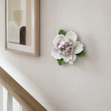 Small Ruffled Peony Ceramic Wall Flower in Plum Purple Accent mounted beside a small abstract print on a stair landing.
