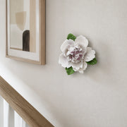 Small Ruffled Peony Ceramic Wall Flower in Plum Purple Accent mounted beside a small abstract print on a stair landing.