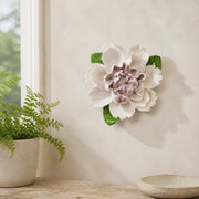 Medium Ruffled Peony Ceramic Wall Flower in Plum Purple Accent mounted beside a small fern on a sunroom wall.