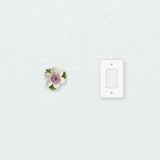 Petite fleur de lotus – Accent violet prune près d’une plaque d’interrupteur pour l’échelle