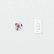 Petite fleur de lotus – Accent violet prune près d’une plaque d’interrupteur pour l’échelle