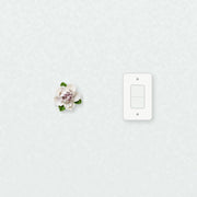 Small Ruffled Peony Ceramic Wall Flower in Plum Purple Accent beside a plain light-switch wall plate for scale.
