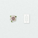 Medium Ruffled Peony Ceramic Wall Flower in Plum Purple Accent beside a plain light-switch wall plate for scale.
