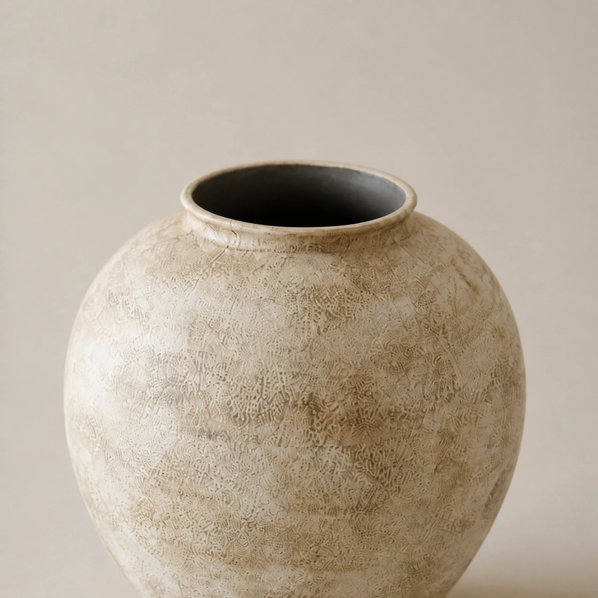 Close view of the Small vase's rounded lip, dark opening, granular ceramic surface, and taupe mottling.