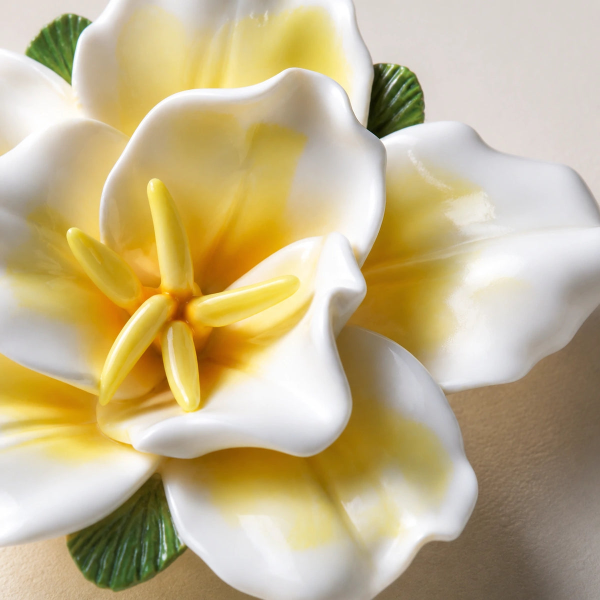 Close view of yellow glaze pooling, curled white petals and the pointed center of a ceramic lily magnet.
