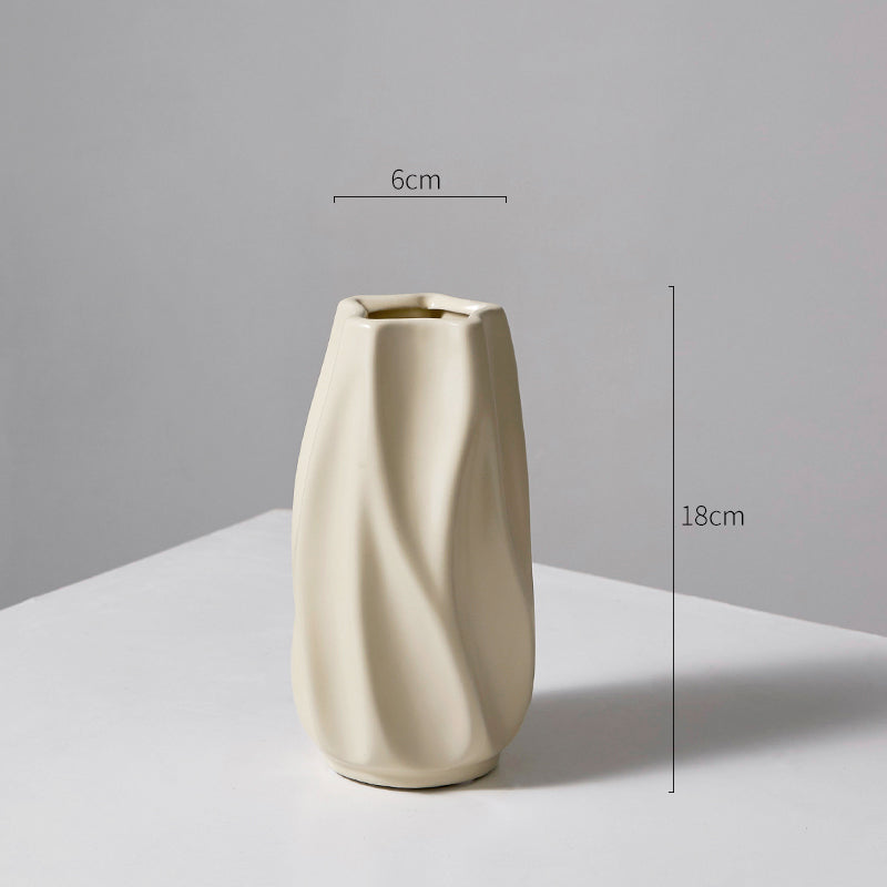 Cream-colored ceramic vase with twisted design, 18cm tall and 6cm wide, on white surface