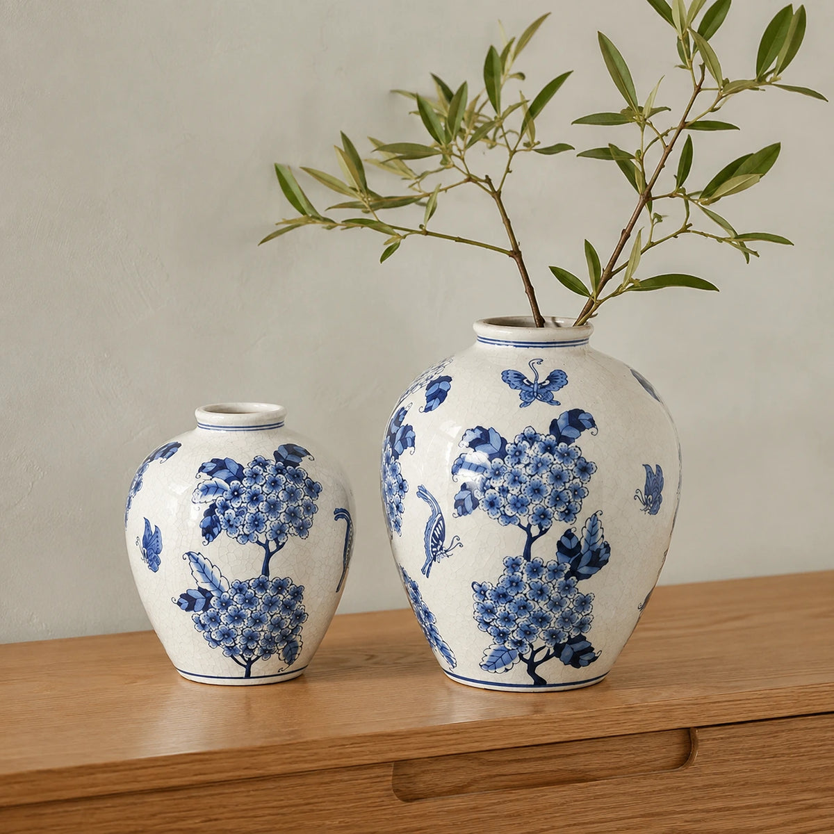 Small and large blue and white vases on an oak console, with leafy branches in the large vase.