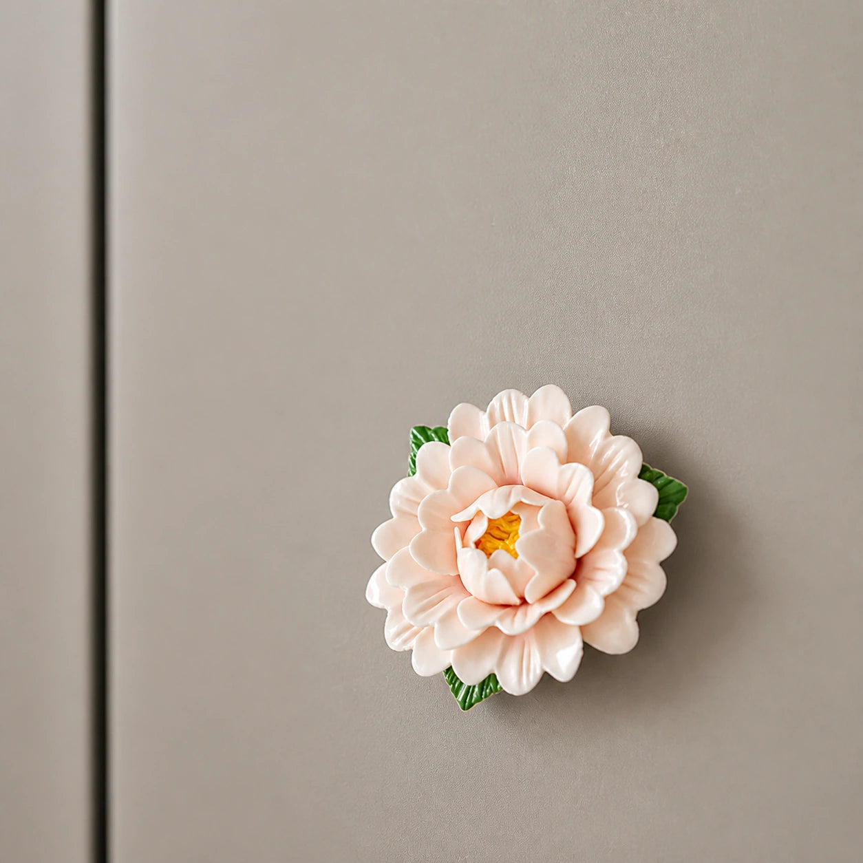 Aimant pivoine en céramique ivoire rosé sur un réfrigérateur gris champignon épuré.